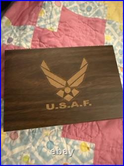 Three United States Air Force (USAF) challenge coins resting in A Wood Case